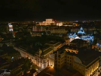 From the massive scale of the Palace of the Parliament to the elegant domes of the historic city center, this aerial view captures the immense beauty and complexity of Romania's capital, glowing under the dark night sky. A panoramic masterpiece.